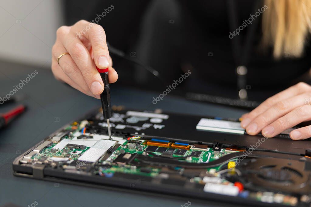 Technician repairing an open laptop on a workbench